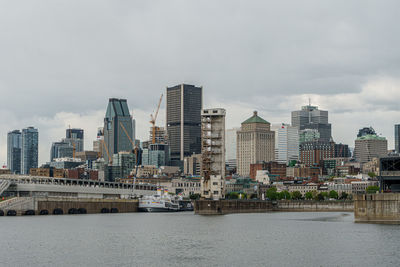 Modern buildings by river against sky in city