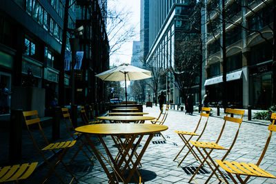 Empty chairs and tables at cafe in city