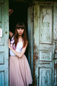 Portrait of young woman standing at doorway