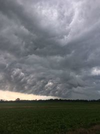 Scenic view of field against storm clouds