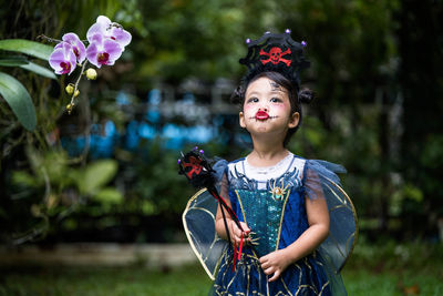 Portrait of girl standing against pink flowering plants