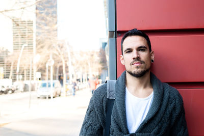 Front view of a fashionable young man standing against red wall