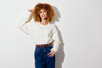 Portrait of young woman standing against white background