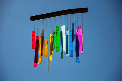 Colorful wind chime hanging against clear blue sky