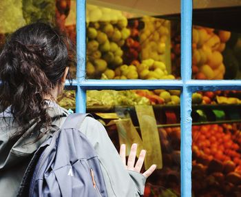 Rear view of woman looking towards fruits seen through window