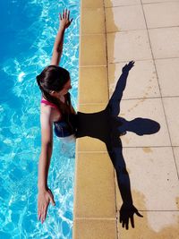 High angle view of girl with arms outstretched standing in swimming pool