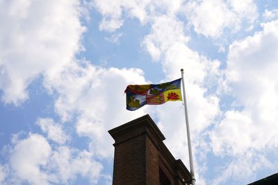 Low angle view of flag amidst buildings against sky