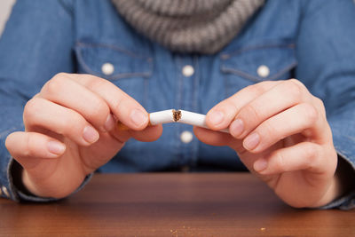 Midsection of woman breaking cigarette at table