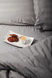 Close-up of cookies with coffee in plate on bed