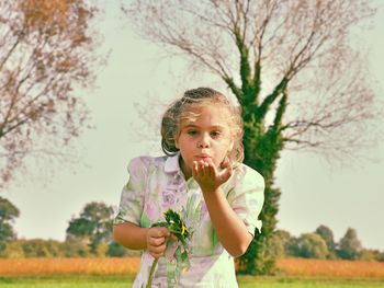 Portrait of happy girl standing on field against clear sky