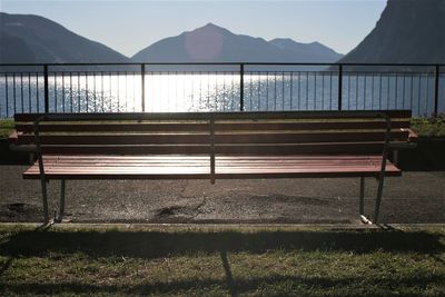 Empty bench by sea against sky