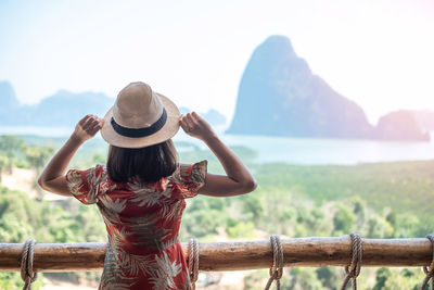 Rear view of woman looking at mountains against sky