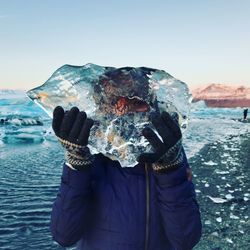 Midsection of person standing by sea against clear sky during winter