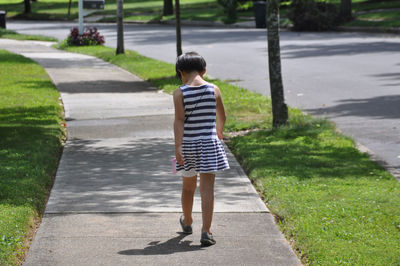 Rear view of girl walking on footpath