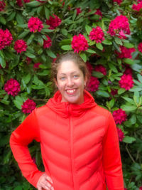 Portrait of smiling woman standing by pink flowering plants