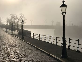 Walkway by river against sky