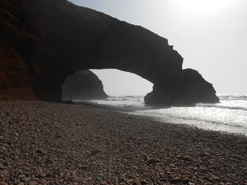 Rock formation on beach against sky