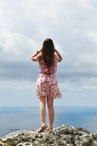 Full length of woman standing on rock against sea