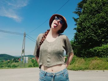 Young woman standing against sky