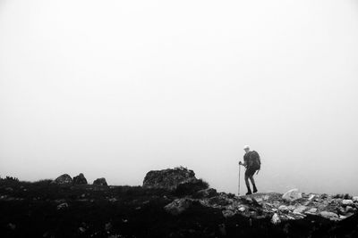 Rear view of man standing on rock against sky