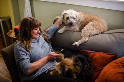 Mid 40's woman sitting on chair with her two large dogs