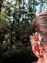 Portrait of woman with pink flower in forest