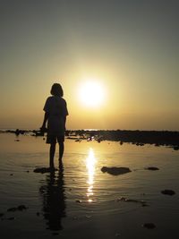 Full length of silhouette man standing at beach during sunset