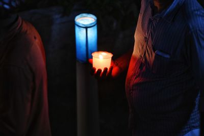 Lit candle in a cup with dark background 