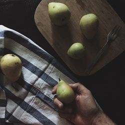 Cropped image of person holding pear at table