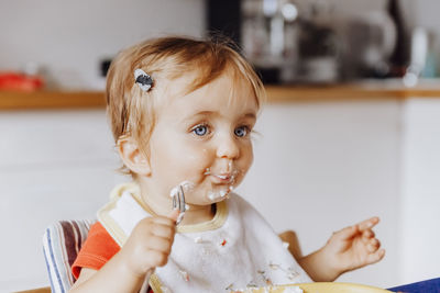 Cute baby girl with messy face in kitchen