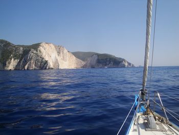 Sailboat sailing on sea against clear blue sky