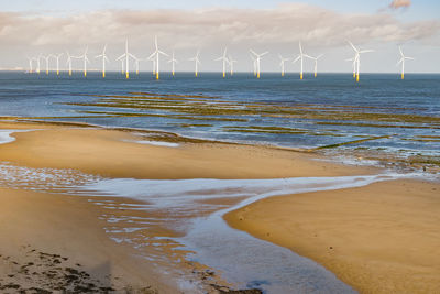 Traditional windmill on beach against sky