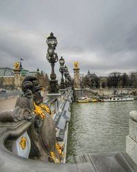 Statue in city against cloudy sky