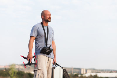 Mid adult man looking away while standing against clear sky