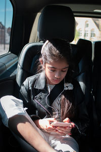 Midsection of girl using phone while sitting in car