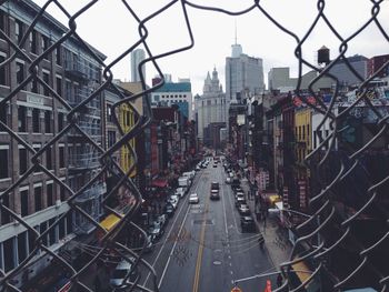 View of city street through broken chainlink fence