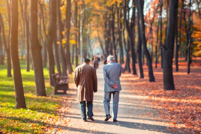 Rear view of couple walking on street during autumn