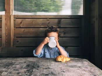 Boy having coffee and croissant in cafe