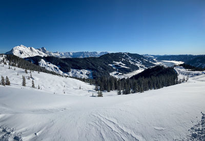 Scenic view of snow covered mountains against clear blue sky