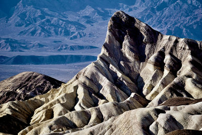 Scenic view of jagged white mountains against distant barren landscape