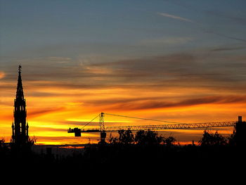 Silhouette landscape against cloudy sky during sunset