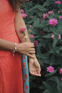 Midsection of woman standing by pink flowering plants