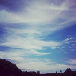 Low angle view of trees against cloudy sky