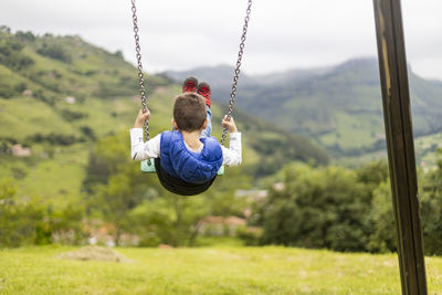 Rear view of boy swinging in playground