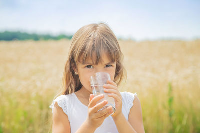 Portrait of young woman drinking water in field