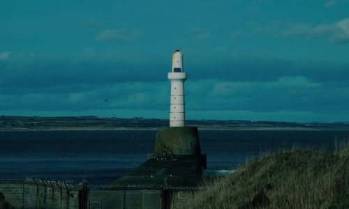 Lighthouse by sea against sky