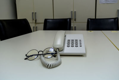 High angle view of telephone and eyeglasses on table