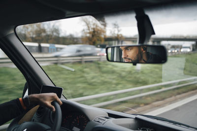 Man is reflecting on rear-view mirror of delivery van