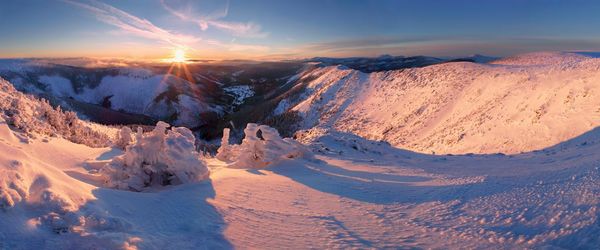 Scenic view of snow covered mountains against sky during sunset