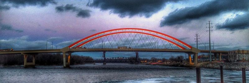 Bridge over sea against cloudy sky